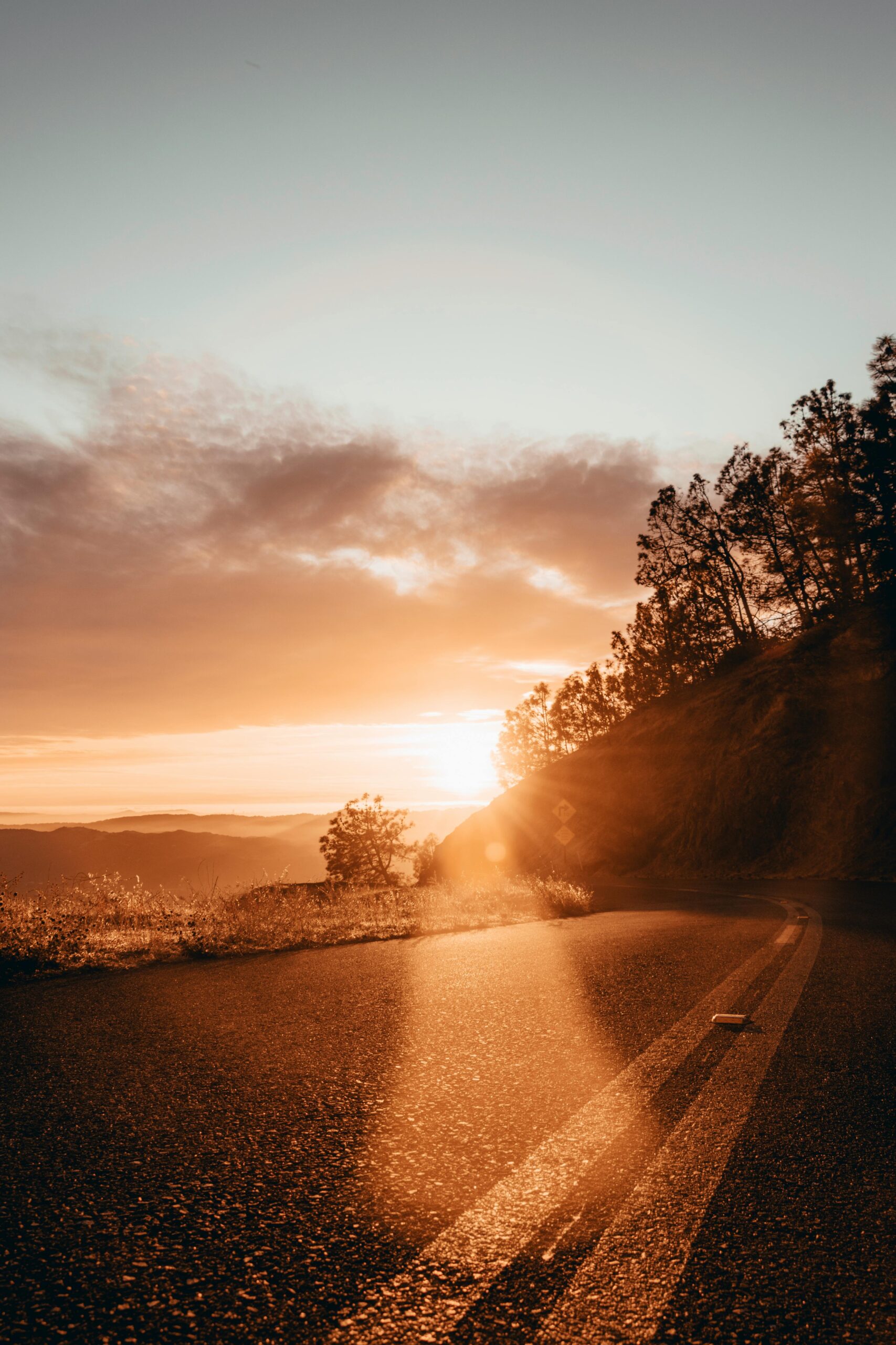 Peaceful countryside road at golden sunset with dramatic sky and warm tones.