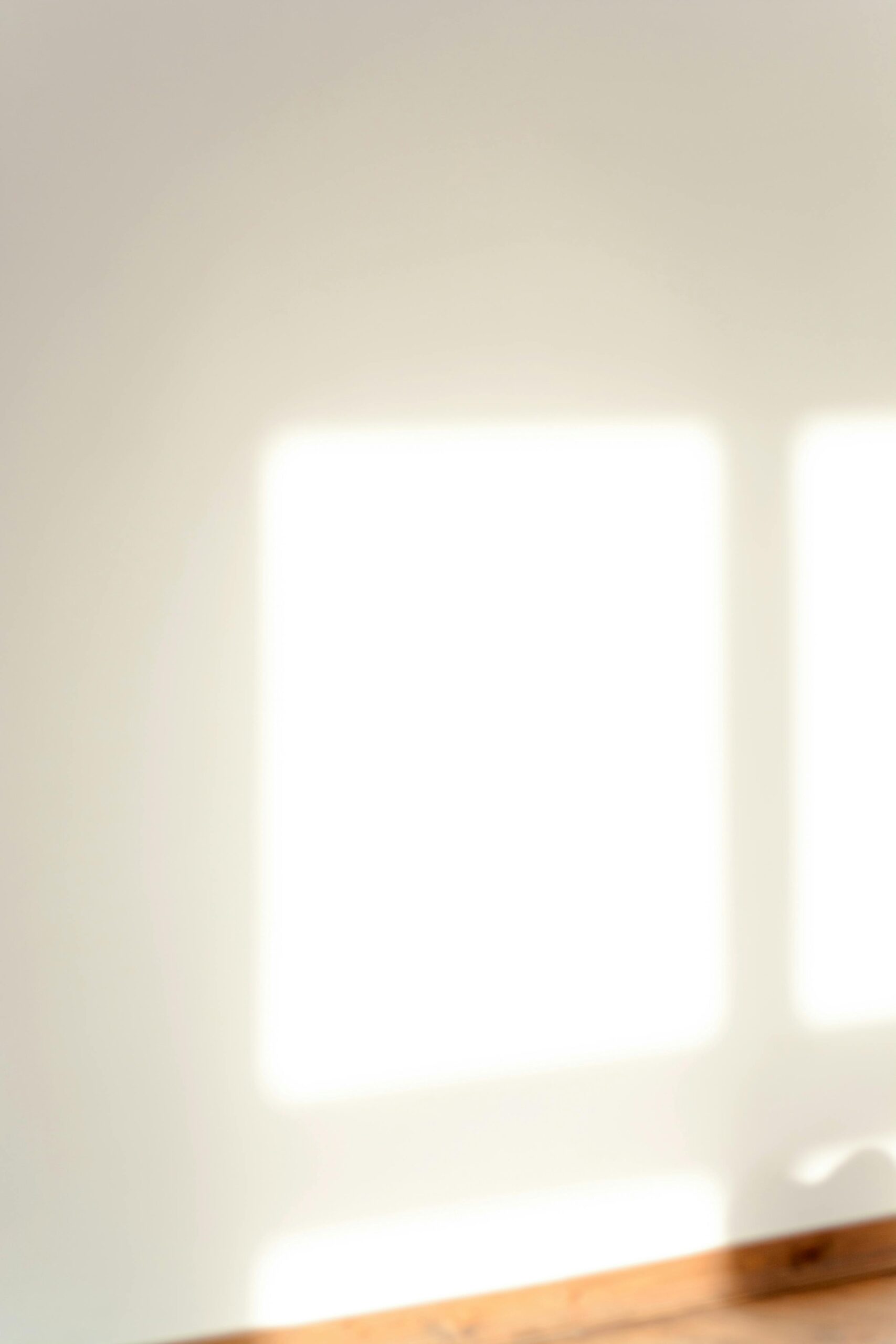 White clear wall with shadows of square windows in light room with bright sunlight in modern apartment on sunny day